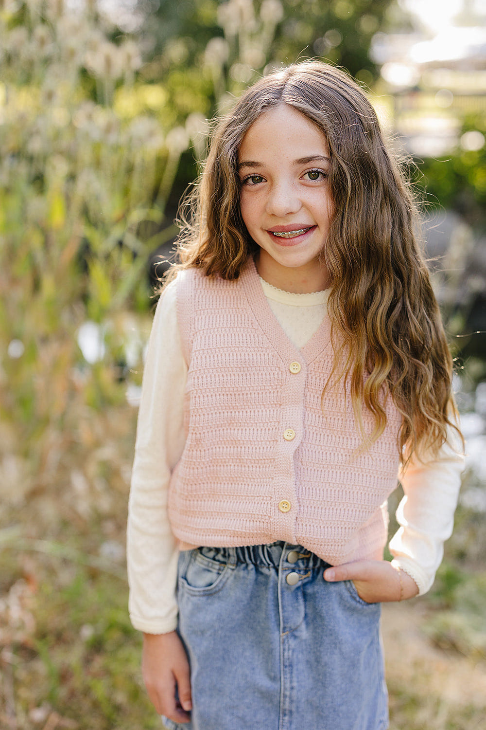 Pink knit button-down vest for babies, perfect for cozy playtime and stylish outfits.