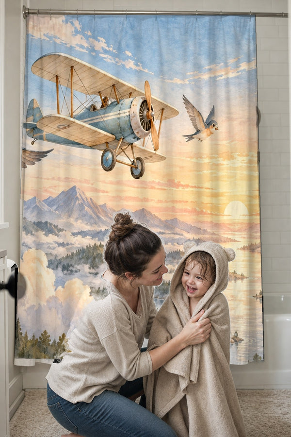 Mom drying her toddler in a hooded towel in front of the Birds and Biplane shower curtain