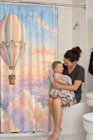 Mom holding her baby on the tub edge next to the Sunrise Hot Air Balloon shower curtain