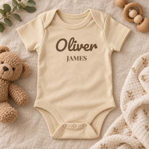 Styled flat lay of the First and Middle Name baby bodysuit