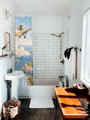 Coastal Explorer shower curtain hanging on the rod over a white bathtub