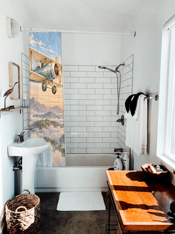 Birds and Biplane shower curtain hanging on the rod over a white bathtub