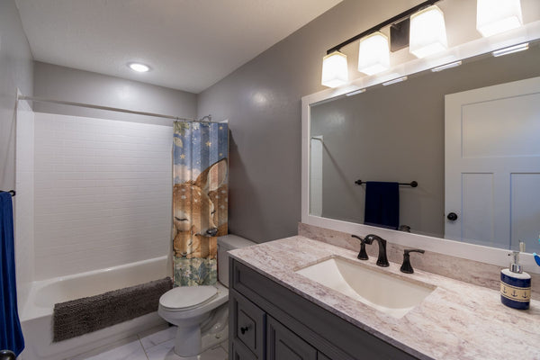 Woodland Friends shower curtain pulled open in a gray kids bathroom