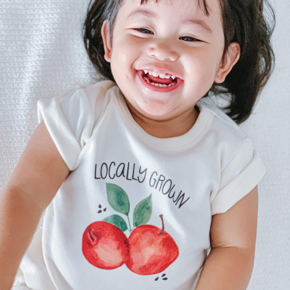 Graphic short sleeve bodysuit for babies, featuring locally grown materials and a playful design.