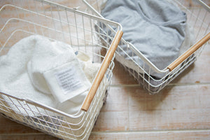 Wire basket in two sizes, featuring steel and wood design, ideal for laundry organization.