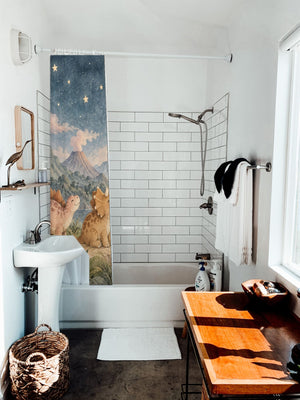 Moonlit Dinosaurs shower curtain hanging on the rod over a white bathtub