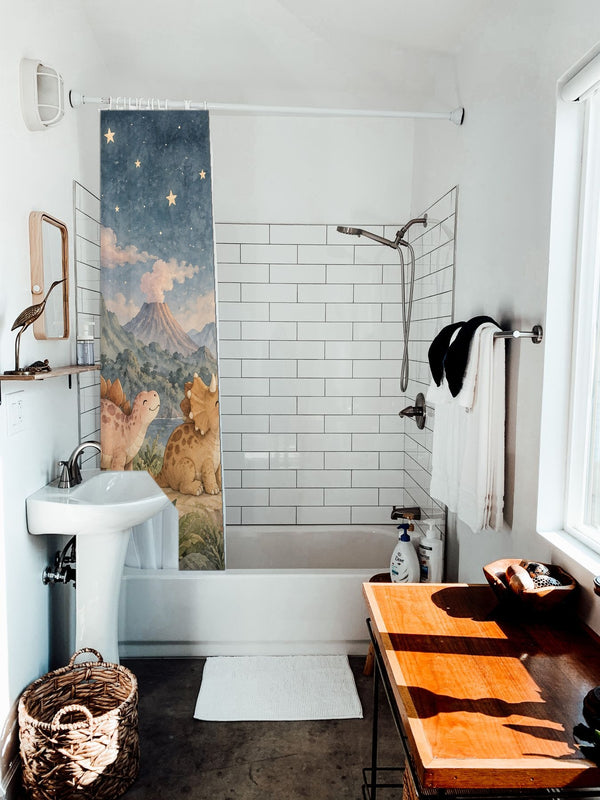 Moonlit Dinosaurs shower curtain hanging on the rod over a white bathtub