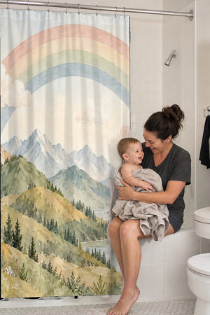 Mom holding her baby on the tub edge next to the Golden Valley Rainbow shower curtain