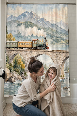 Mom drying her toddler in a hooded towel in front of the Mountain Bridge Train shower curtain