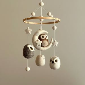 Low angle close up of the wool felt owl mobile against a soft cream wall