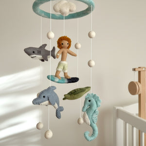 Low angle view of the felt ocean mobile against a blurred cream wall in warm light