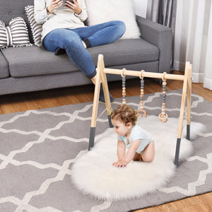 Portable wooden baby gym with teething toys, perfect for newborns. Angle 17 view showcasing activity bar features.