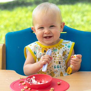 "Busy Bees Bapron for babies, featuring a colorful bee design, angled view showcasing its practical and stylish design."