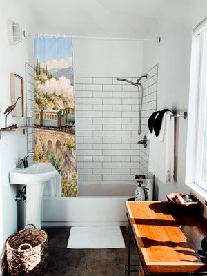 Coastal Train shower curtain hanging on the rod over a white bathtub