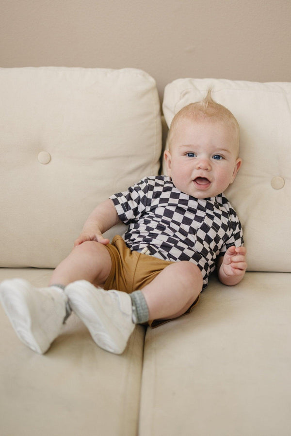 Black checkered bamboo tee for babies, stylish and comfortable, angled view showcasing design and fabric texture.