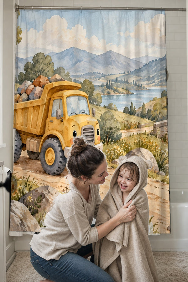 Mom drying her toddler in a hooded towel in front of the Dump Truck Road shower curtain