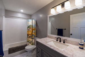 Dump Truck Road shower curtain pulled open in a gray kids bathroom