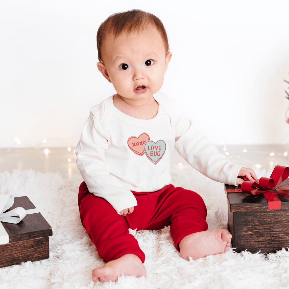 Long sleeve graphic bodysuit featuring candy hearts design for babies. Perfect for comfort and style.