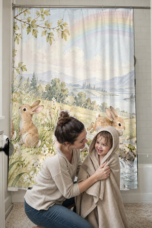 Mom drying her toddler in a hooded towel in front of the Rainbow Meadow Bunny shower curtain