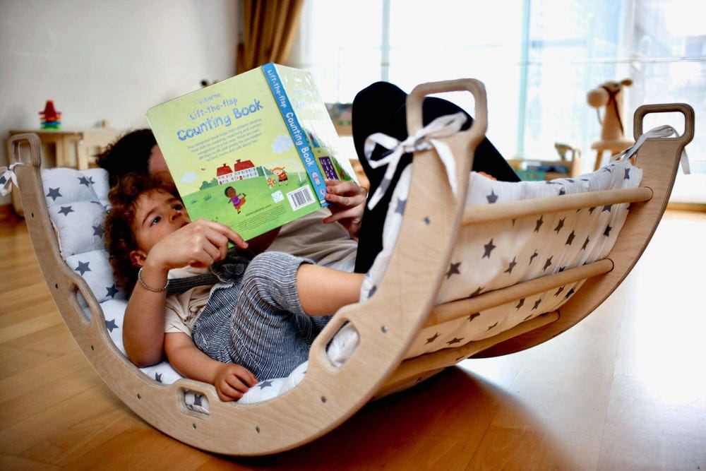 Climbing arch rocker with white star pillow for imaginative play, perfect for babies and toddlers.