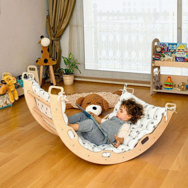 Climbing arch rocker with white star pillow for imaginative play, perfect for babies and toddlers.