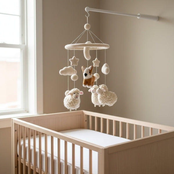 Handmade felt corgi and sheep baby mobile hanging softly above a crib in a nursery