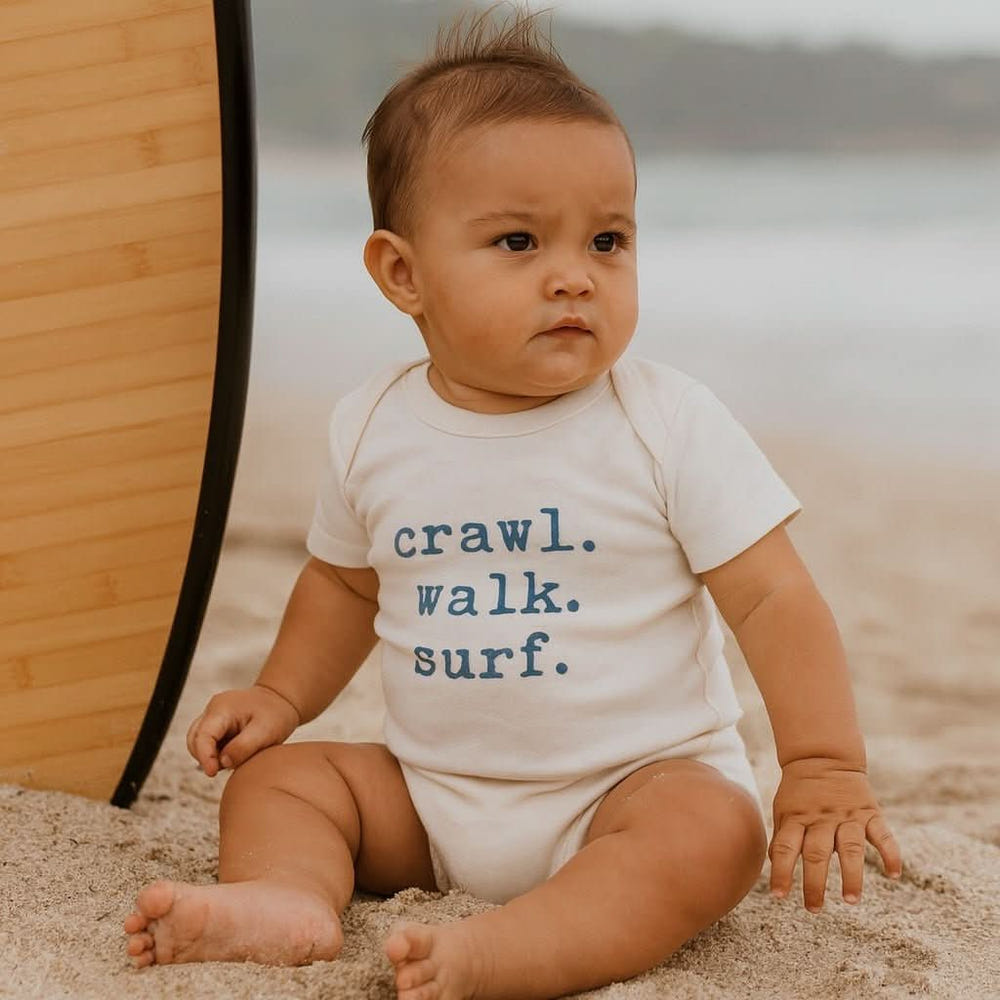 Graphic bodysuit for babies featuring "Crawl Walk Surf" design - perfect for playful and stylish outfits.