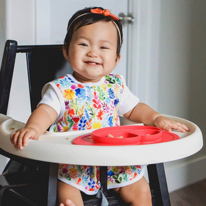 Rainbow watercolor floral bapron for babies, showcasing vibrant colors and a unique design from an angled view.