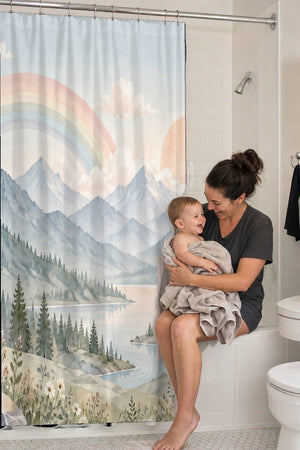Mom holding her baby on the tub edge next to the Alpine Lake Rainbow shower curtain