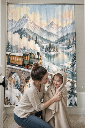 Mom drying her toddler in a hooded towel in front of the Winter Train shower curtain