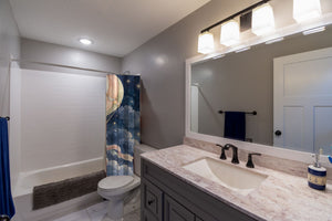 Moonlit Flight Hot Air Balloon shower curtain pulled open in a gray kids bathroom