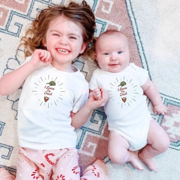 Graphic bodysuit for babies featuring "Love Dad" with a beard design, short sleeves, angle view.