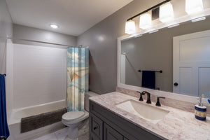 Paper Planes shower curtain pulled open in a gray kids bathroom