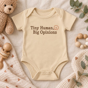 Styled flat lay of the Tiny Human, Big Opinions baby bodysuit