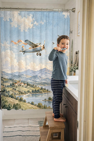 Child brushing teeth in a family bathroom with the Balloon and Plane shower curtain