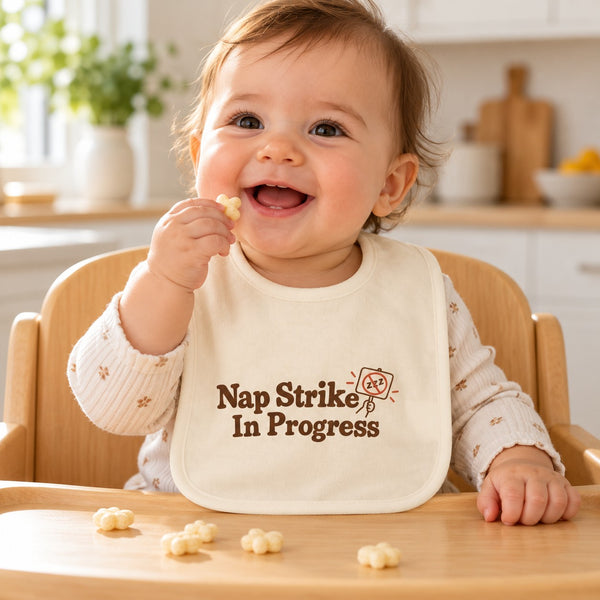 Nap Strike In Progress baby bib in cream, styled photo 1