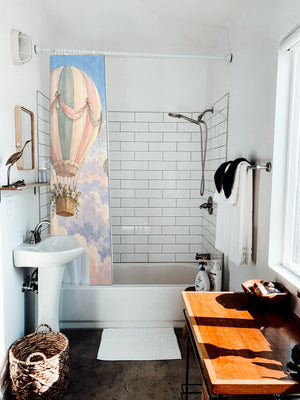 Dreamy Clouds Hot Air Balloon shower curtain hanging on the rod over a white bathtub
