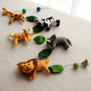 Close up of the felt safari garland's texture, wool animals and leaves on a linen surface.