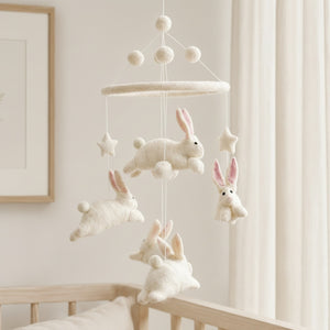Close-up of the felt bunny mobile from a low angle against a softly blurred cream wall