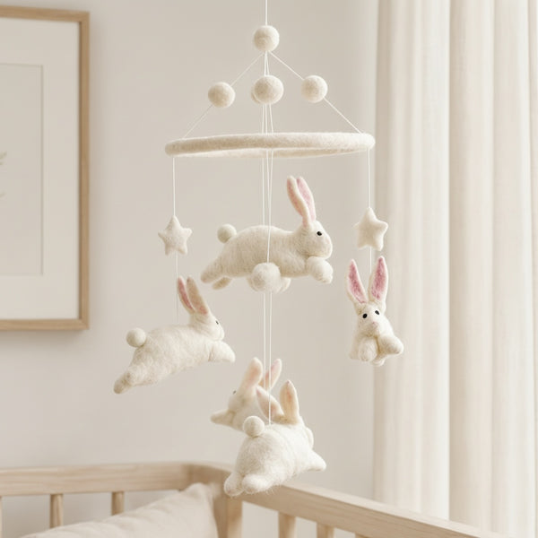 Close-up of the felt bunny mobile from a low angle against a softly blurred cream wall