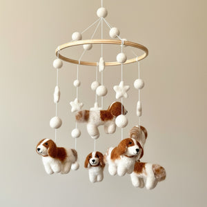 Close up of the felt baby mobile's wool puppies and stars against a soft cream wall