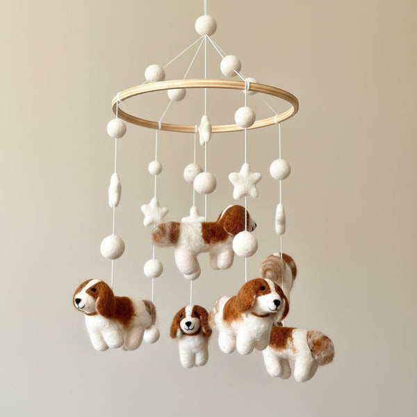 Close up of the felt baby mobile's wool puppies and stars against a soft cream wall