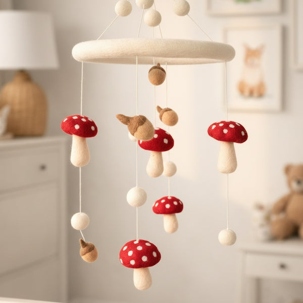 Low angle view of the felt wool mushroom and acorn mobile against a soft cream wall