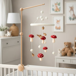 Felt mushroom baby mobile hanging above a light wood crib in a calm, sunlit nursery