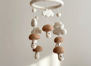 Low angle close up of the felt mushroom baby mobile against a softly blurred cream wall in warm light