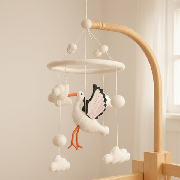 Close-up of the felt stork mobile from a low angle against a softly blurred cream wall, warm light.