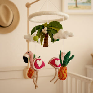Felt tropical baby mobile seen from a low angle against a softly blurred cream wall