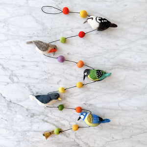 Felt bird garland laid flat, showing five needle felted wool birds and colorful felt balls