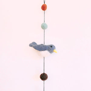 Close up of a felt blue and white bird on the garland, hanging between felt ball beads