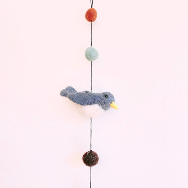Close up of a felt blue and white bird on the garland, hanging between felt ball beads